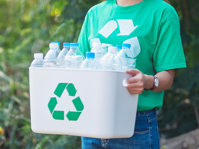 An asian woman collecting garbage and holding a recycle bin with