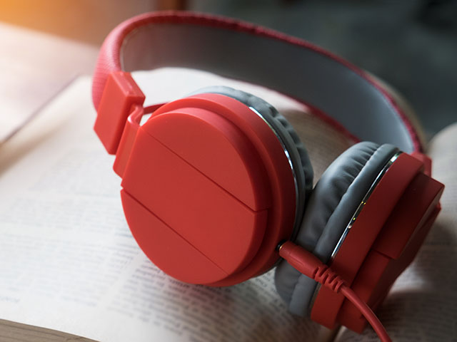 Concept of audiobook. Books on the table with headphones put on